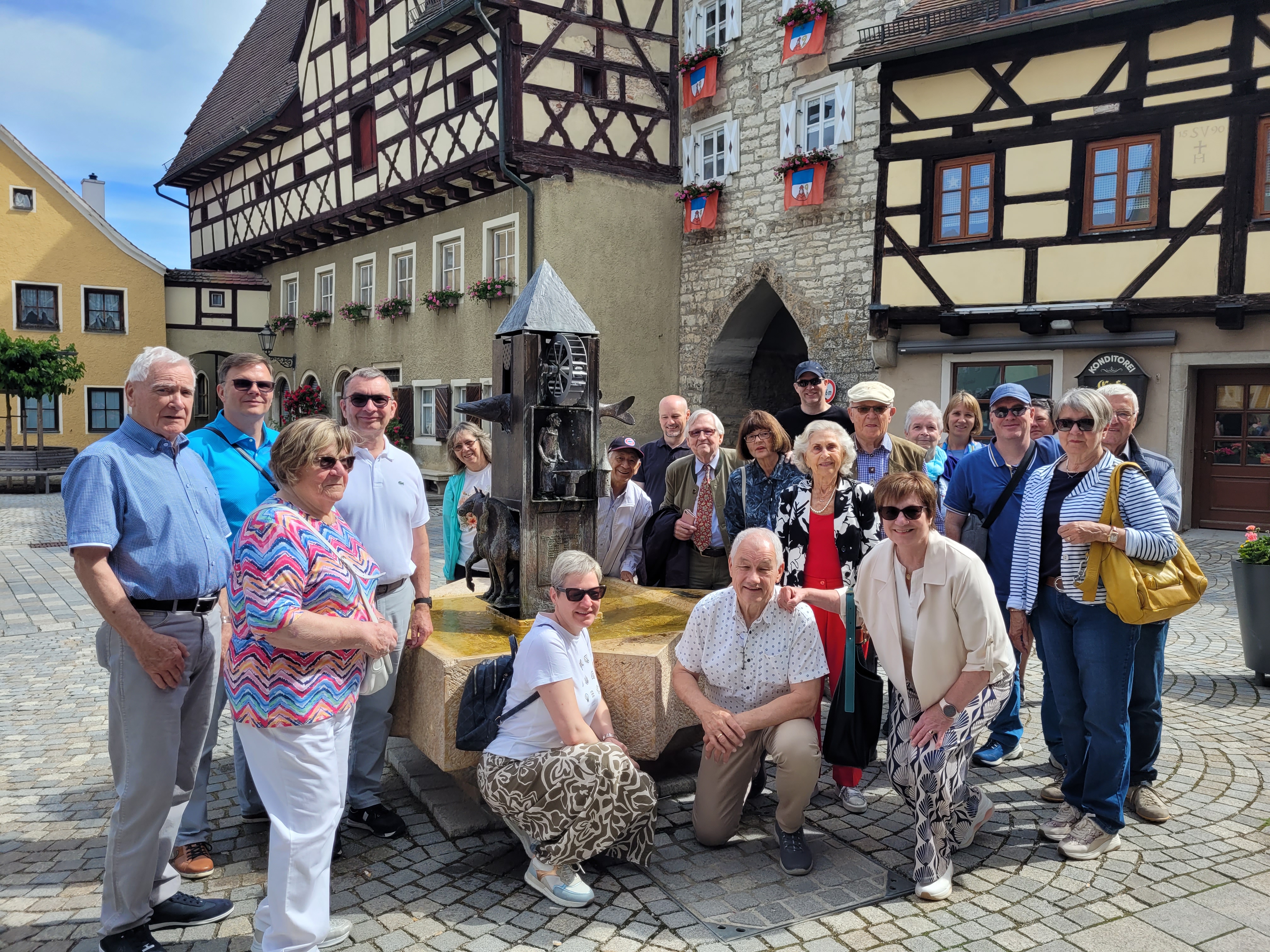 Ordensmitglieder als Gruppe vor einem Brunnen in einer fränkischen Altstadt